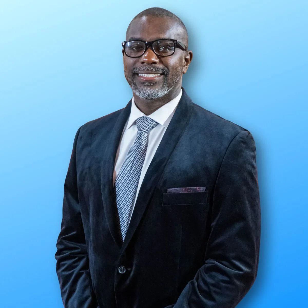 pastorJeff Man in a dark suit, glasses, and tie smiling against a light blue background.